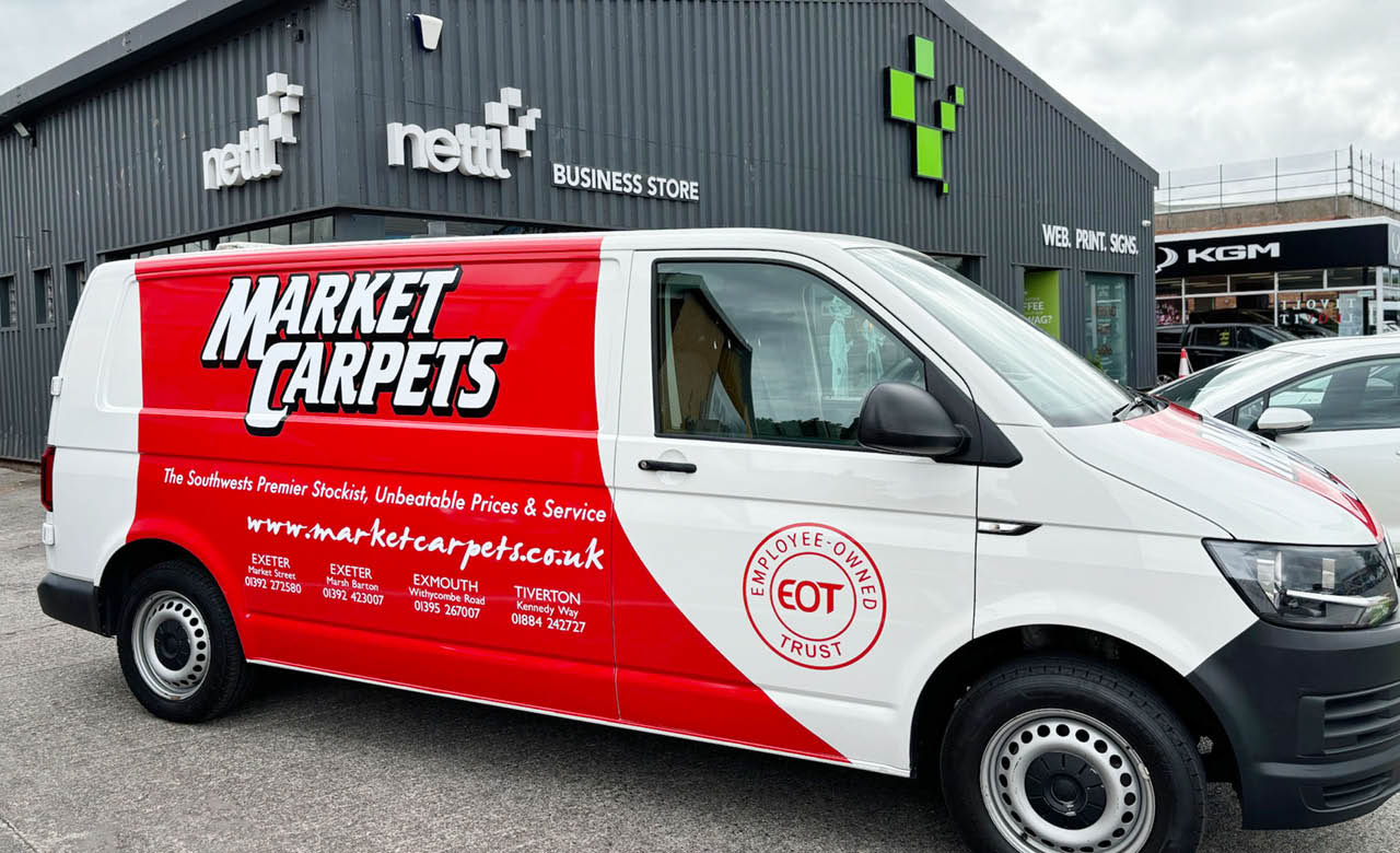 The Market Carpets van parked outside Nettl of Exeter showcasing the partial vehicle graphics wrap.