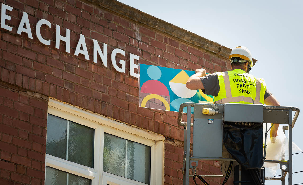 Joe lifting the acrylic sign into position on the Seachange building.