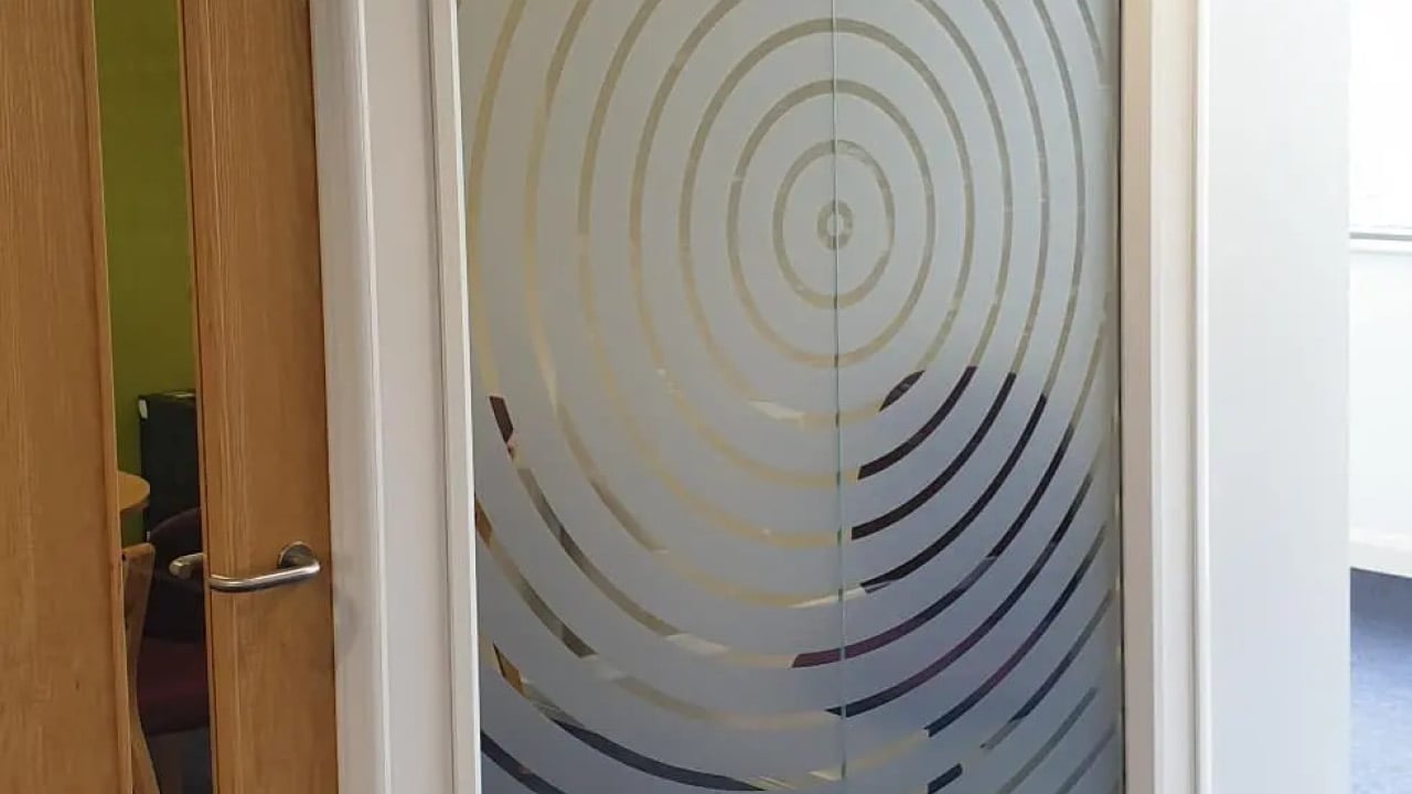 Vinyl cut circular shapes on an large sheet of glass within an office space.