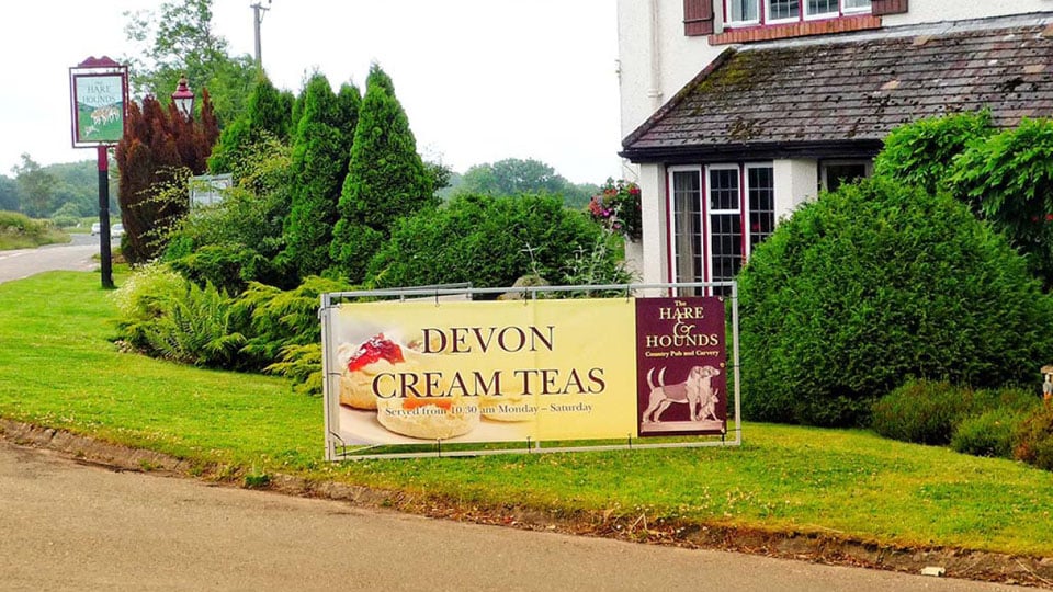 A roadside PVC banner for Hare and Hounds pub.