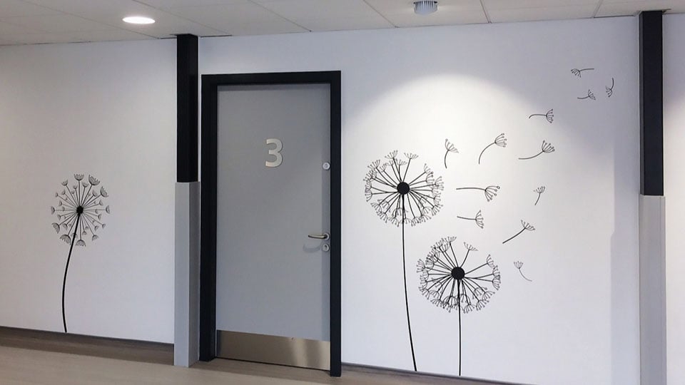 This image shows dandelions blowing in the breeze, this wall graphic has been installed on a white wall to better showcase the effect.